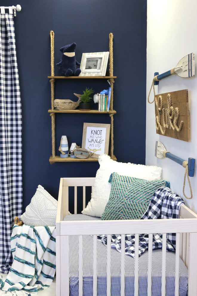 Photo of a small beach style nursery for boys in Austin with blue walls, laminate floors and beige floor.