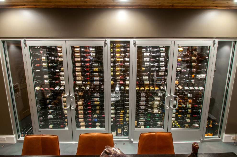 Photo of a mid-sized contemporary wine cellar in Nashville with laminate floors, storage racks and grey floor.