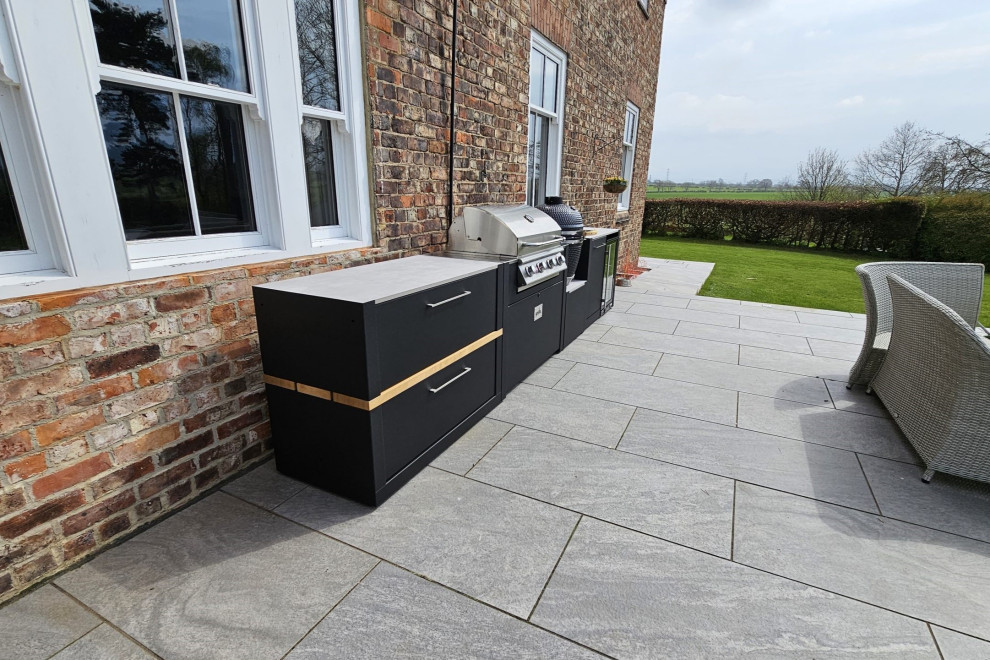 Photo of a medium sized contemporary back patio in Other with an outdoor kitchen, natural stone paving and no cover.