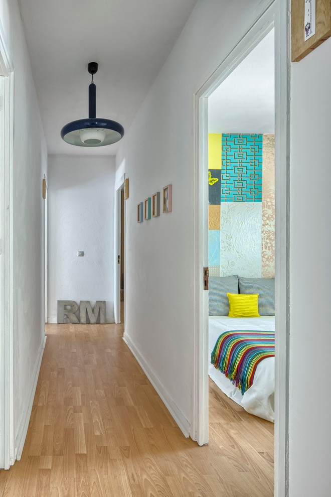 Photo of a mid-sized contemporary hallway in Other with white walls and light hardwood floors.