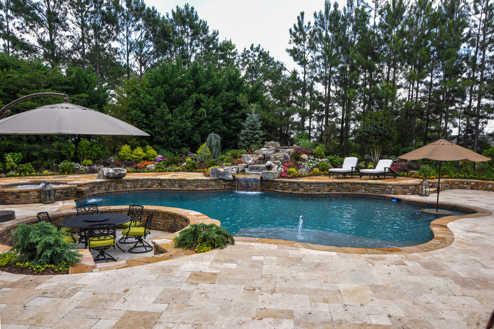 Inspiration for a large traditional backyard custom-shaped natural pool in Atlanta with a water feature and natural stone pavers.