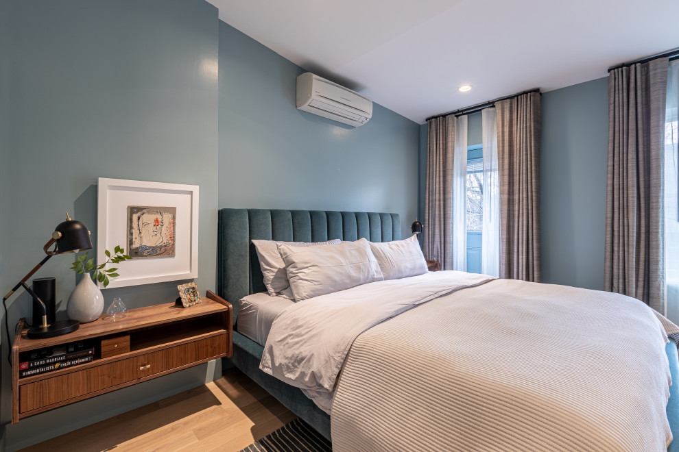 Imagen de dormitorio principal y blanco contemporáneo grande sin chimenea con paredes azules, suelo de madera clara y suelo marrón