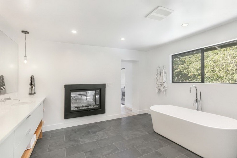Photo of a large modern master bathroom in Sacramento with flat-panel cabinets, white cabinets, a freestanding tub, a curbless shower, a two-piece toilet, gray tile, white tile, marble, white walls, slate floors, an undermount sink, grey floor, an open shower and white benchtops.