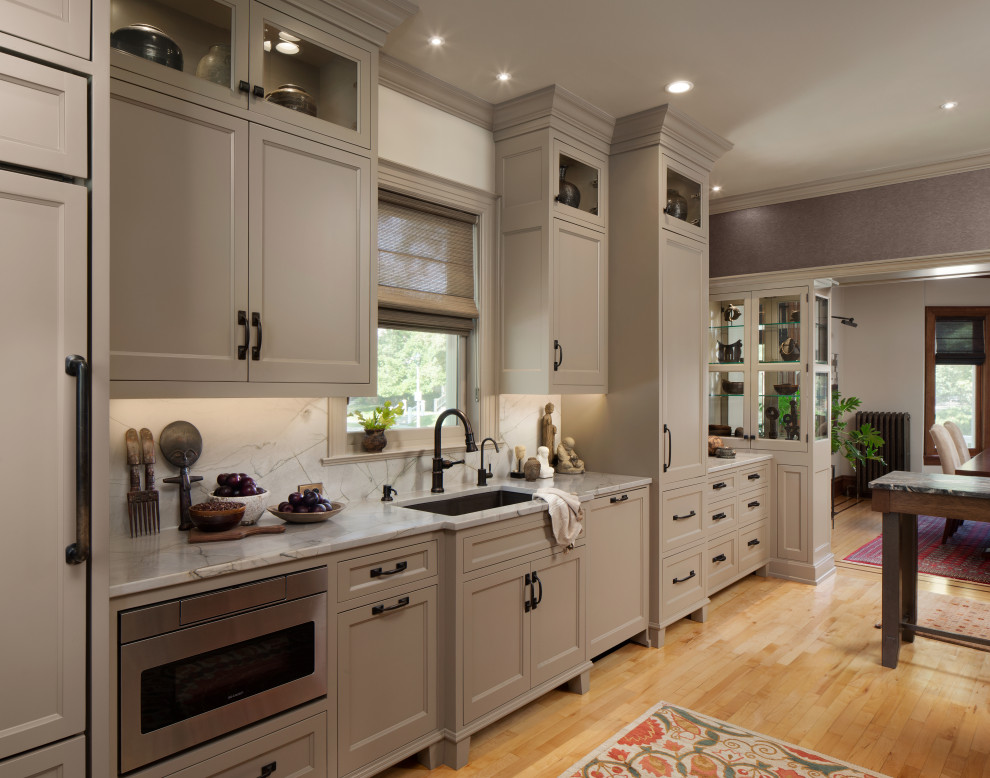 Asian kitchen in Nashville with an undermount sink, shaker cabinets, grey cabinets, panelled appliances, medium hardwood floors, with island, brown floor and grey benchtop.