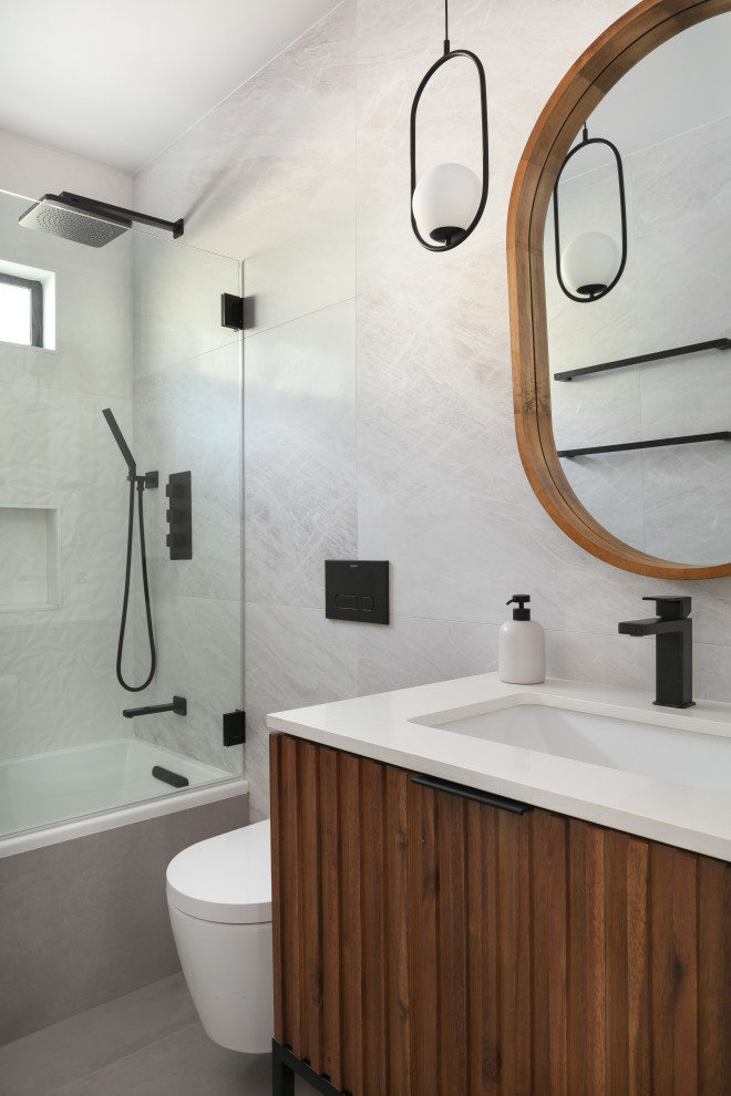 Idéer för ett litet modernt vit en-suite badrum, med möbel-liknande, skåp i mörkt trä, ett platsbyggt badkar, en dusch/badkar-kombination, en vägghängd toalettstol, grå kakel, porslinskakel, klinkergolv i porslin, ett undermonterad handfat, bänkskiva i kvarts, grått golv och med dusch som är öppen