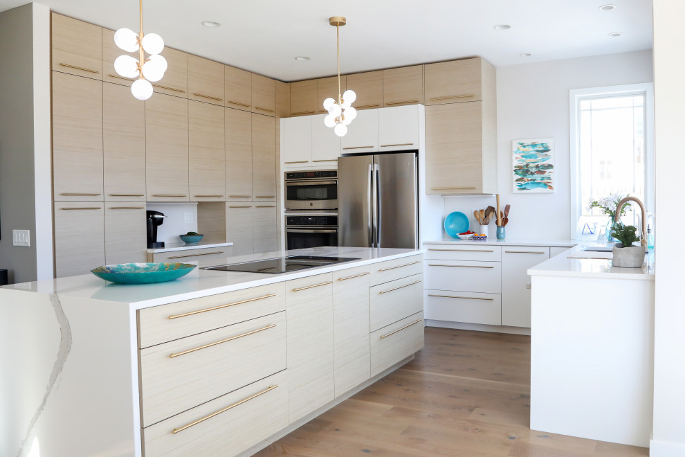 Mid-sized contemporary u-shaped open plan kitchen in Other with a single-bowl sink, flat-panel cabinets, light wood cabinets, quartz benchtops, stainless steel appliances, with island, brown floor, white benchtop and medium hardwood floors.