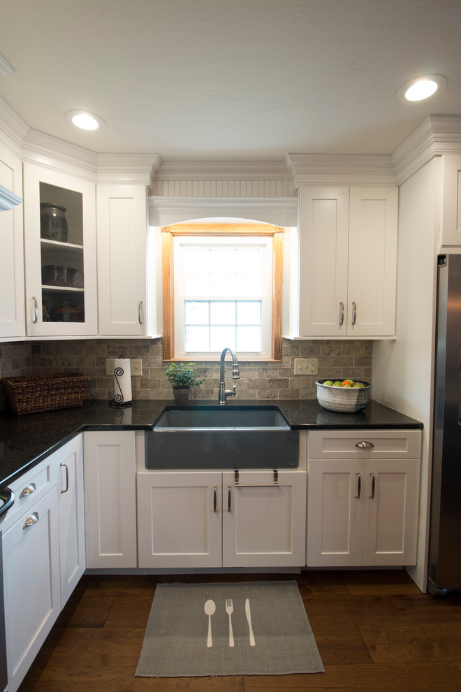 Large transitional l-shaped medium tone wood floor eat-in kitchen photo with an undermount sink, shaker cabinets, white cabinets, granite countertops, gray backsplash, stone tile backsplash, stainless steel appliances and an island
