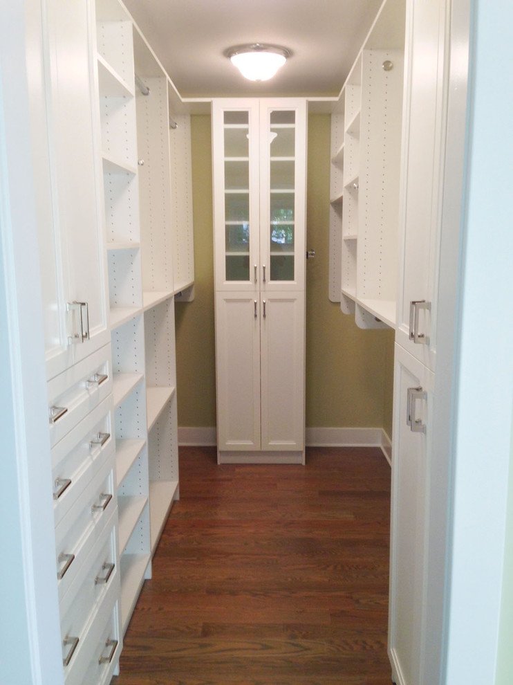 This is an example of a contemporary gender-neutral walk-in wardrobe in New York with shaker cabinets, white cabinets and medium hardwood floors.