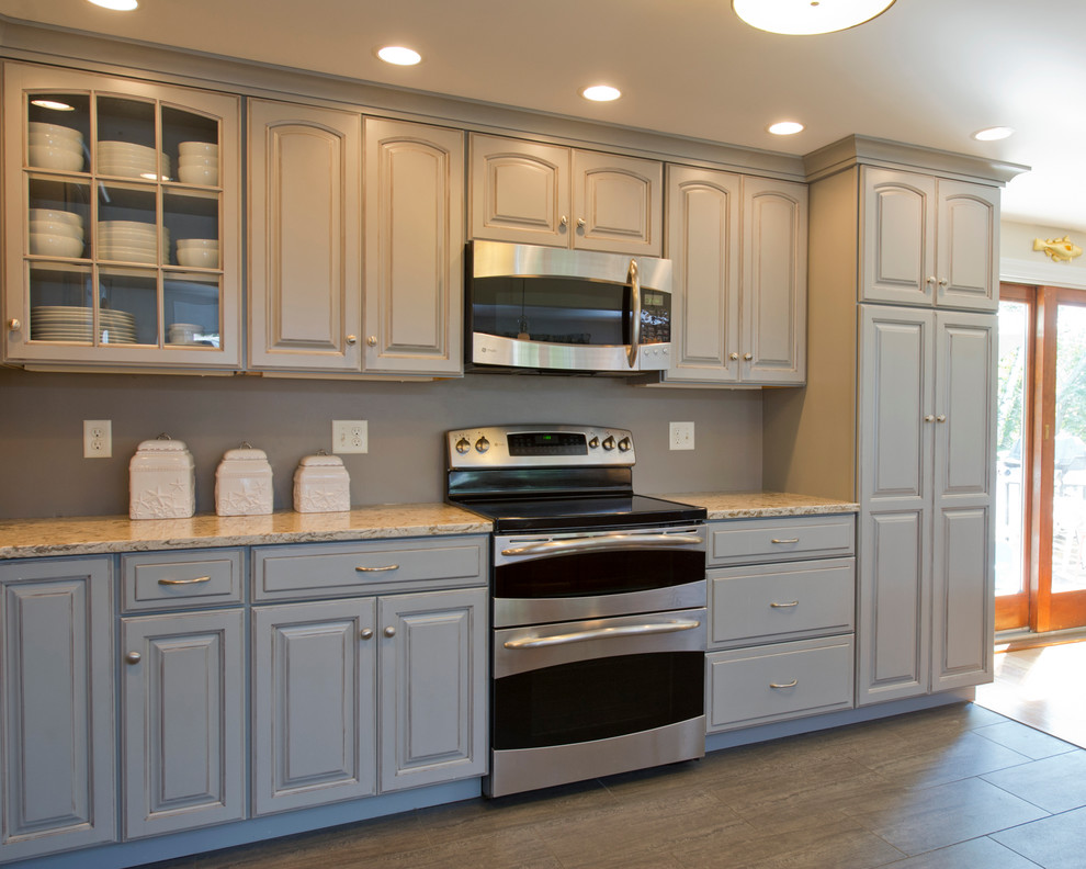 Inspiration for a large transitional l-shaped eat-in kitchen in Boston with an undermount sink, raised-panel cabinets, grey cabinets, quartz benchtops, grey splashback, stainless steel appliances, ceramic floors and with island.