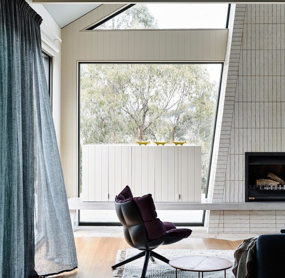 This is an example of a large contemporary open concept living room in Melbourne with beige walls, medium hardwood floors, a standard fireplace, a tile fireplace surround and brown floor.