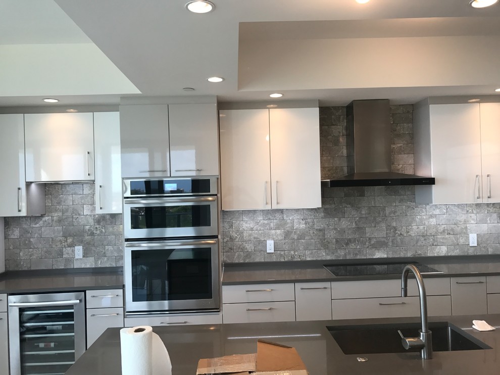 Inspiration for a large modern single-wall enclosed kitchen remodel with a double-bowl sink, marble backsplash and stainless steel appliances