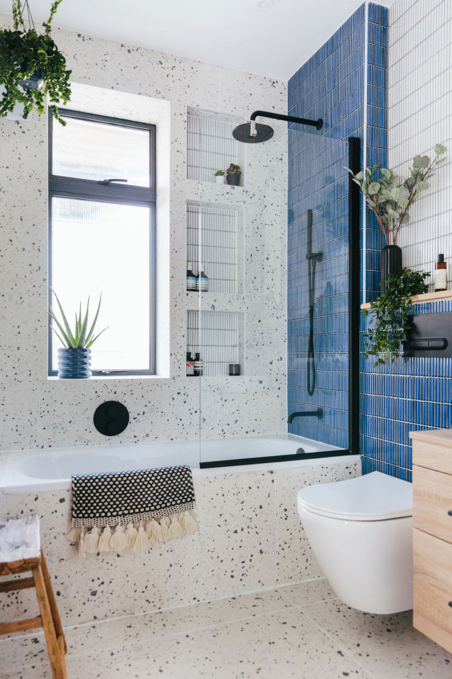 Inredning av ett modernt litet badrum för barn, med skåp i ljust trä, ett platsbyggt badkar, en dusch/badkar-kombination, blå kakel, porslinskakel och träbänkskiva