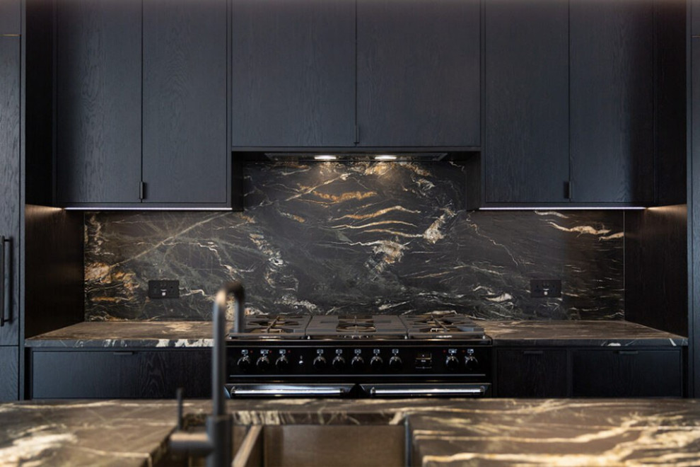 Skandinavisk inredning av ett stort svart linjärt svart kök och matrum, med luckor med profilerade fronter, svarta skåp, bänkskiva i akrylsten, svart stänkskydd, stänkskydd i marmor, en köksö, en enkel diskho, svarta vitvaror, klinkergolv i keramik och beiget golv