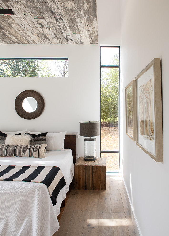 Inspiration for a mid-sized country master bedroom in Austin with white walls, light hardwood floors and brown floor.
