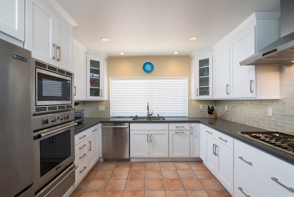 This is an example of a mid-sized modern u-shaped eat-in kitchen in San Diego with a drop-in sink, recessed-panel cabinets, white cabinets, soapstone benchtops, grey splashback, ceramic splashback, stainless steel appliances, terra-cotta floors and a peninsula.