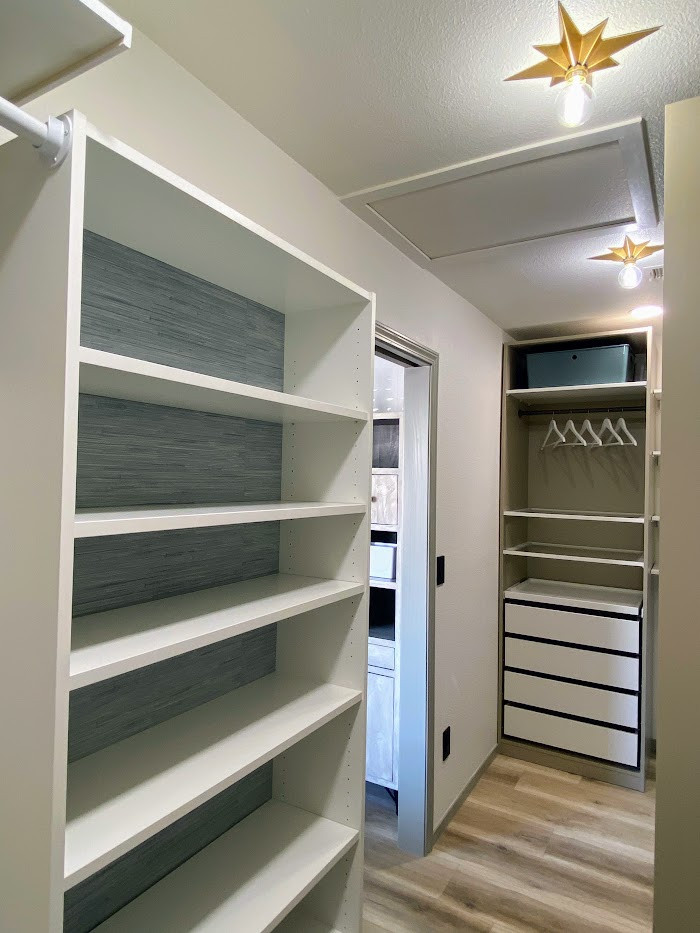Photo of a large modern storage and wardrobe in Las Vegas with glass-front cabinets, white cabinets, vinyl floors and beige floor.