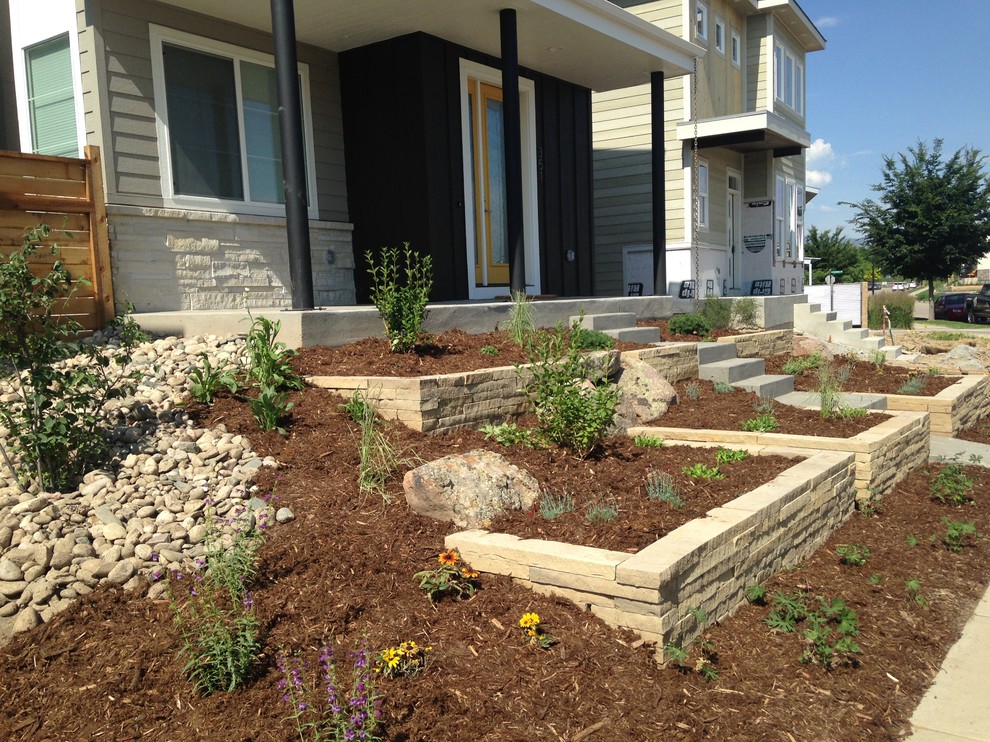 Photo of a small contemporary front yard full sun garden for spring in Denver with a retaining wall and mulch.