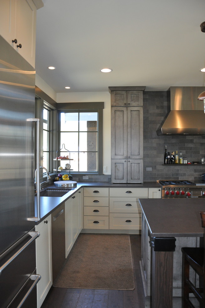 Example of a large mountain style l-shaped medium tone wood floor eat-in kitchen design in Seattle with an undermount sink, shaker cabinets, distressed cabinets, quartz countertops, gray backsplash, stone tile backsplash, stainless steel appliances and an island