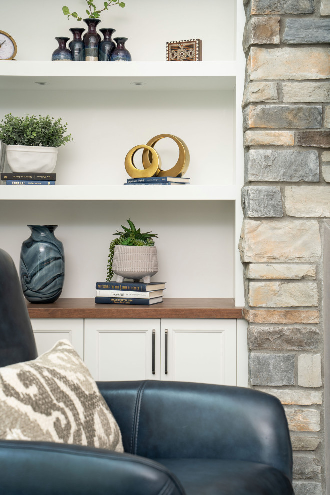 Cette photo montre une salle de séjour chic avec un mur gris, un sol en vinyl, un manteau de cheminée en pierre, un téléviseur fixé au mur et un sol marron.