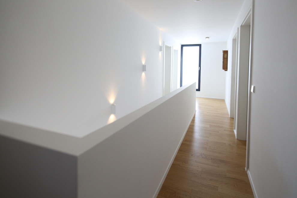 Diseño de recibidores y pasillos contemporáneos de tamaño medio con paredes blancas, suelo de madera clara y suelo beige