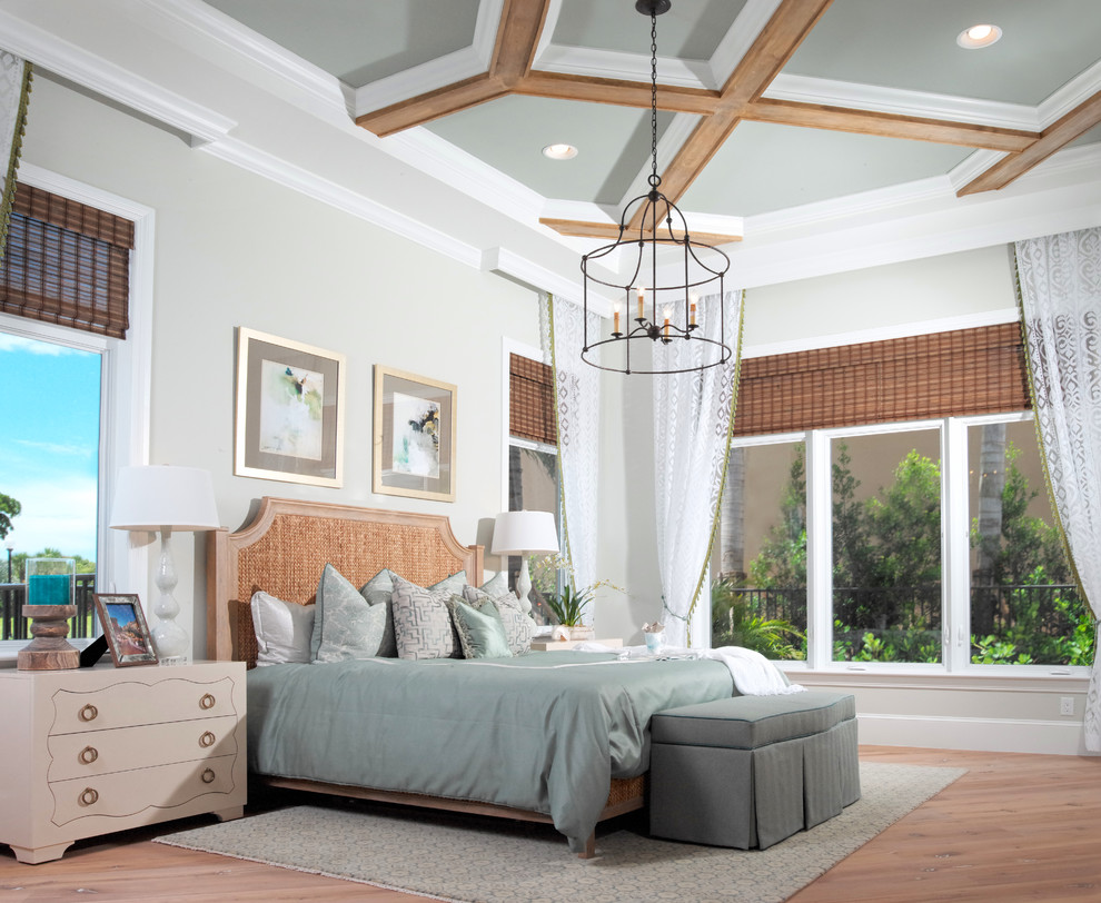 This is an example of a large beach style bedroom in Miami with light hardwood floors.