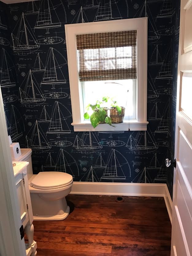 Design ideas for a small beach style powder room in New York with furniture-like cabinets, white cabinets, a two-piece toilet, grey walls, medium hardwood floors and brown floor.