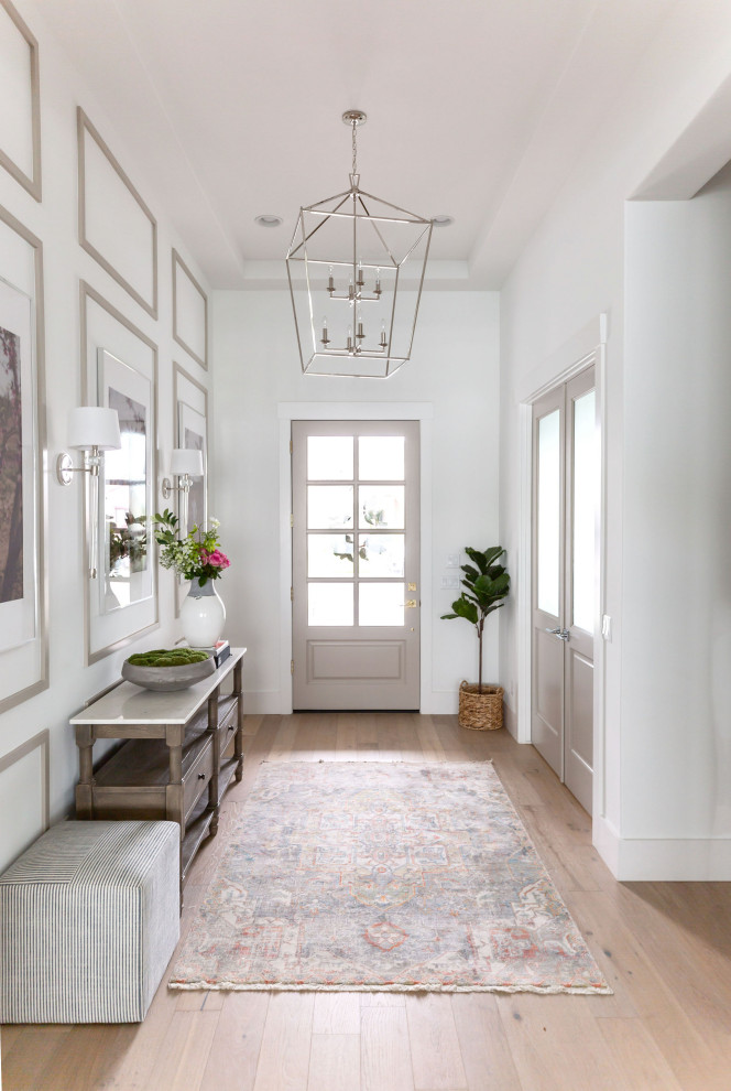 Mid-sized beach style light wood floor, beige floor, tray ceiling and wood wall entryway photo in Phoenix with white walls and a black front door