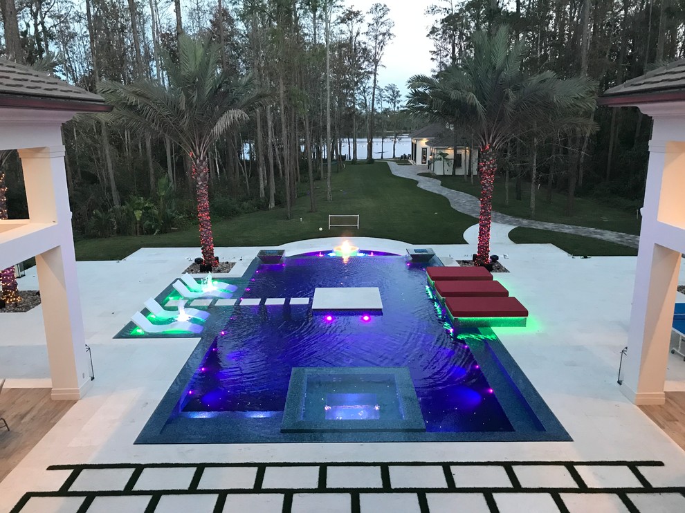 This is an example of an expansive modern backyard custom-shaped infinity pool in Orlando with a water feature.