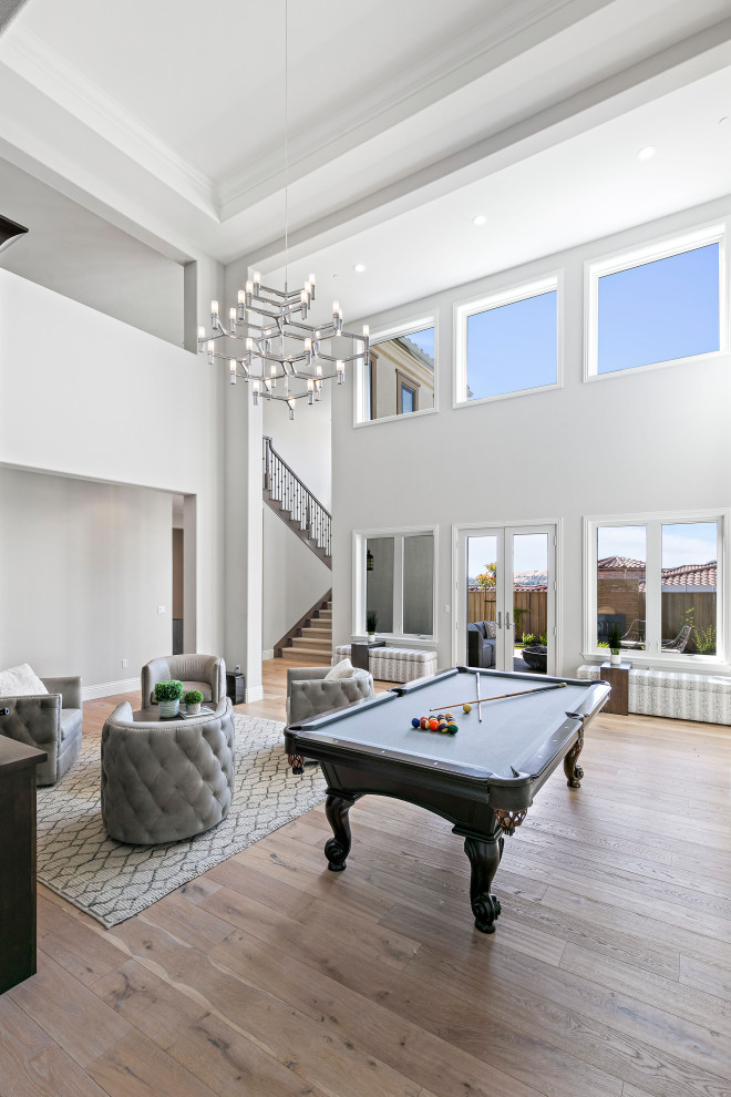 Large transitional open concept family room in San Francisco with a game room, grey walls, light hardwood floors, a wall-mounted tv and coffered.