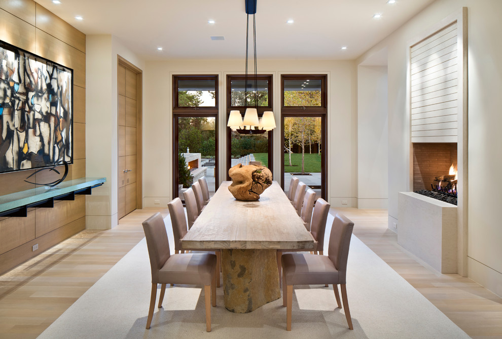 Inspiration for a large contemporary separate dining room in San Francisco with beige walls, light hardwood floors and a standard fireplace.