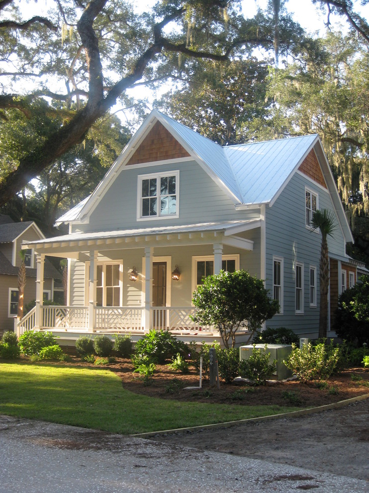 Mid-sized beach style two-storey blue house exterior in Jacksonville with vinyl siding, a gable roof and a metal roof.