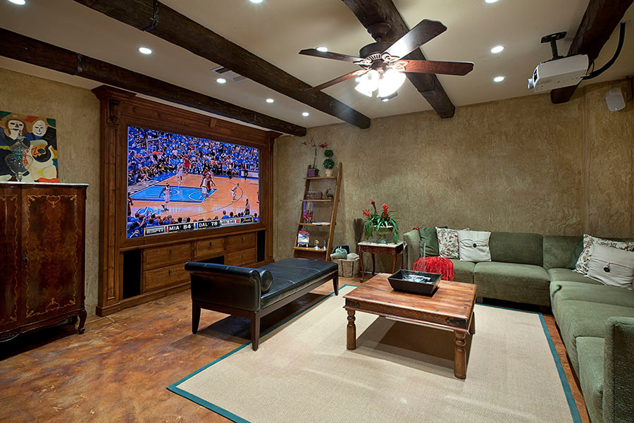 Photo of a large enclosed home theatre in Miami with beige walls, concrete floors, a projector screen and brown floor.