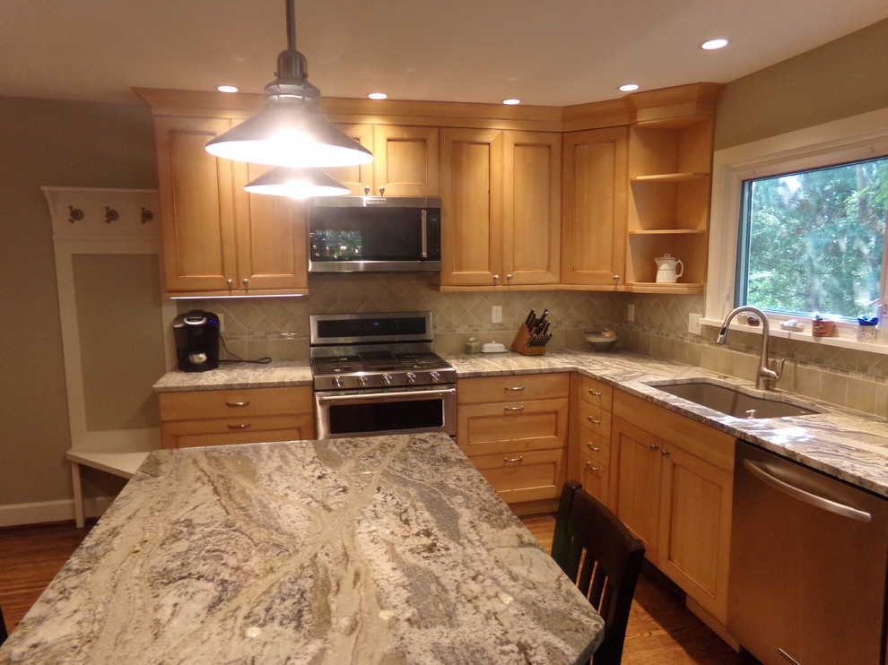 Mid-sized transitional l-shaped medium tone wood floor eat-in kitchen photo in New York with an undermount sink, raised-panel cabinets, light wood cabinets, granite countertops, beige backsplash, subway tile backsplash, stainless steel appliances and an island