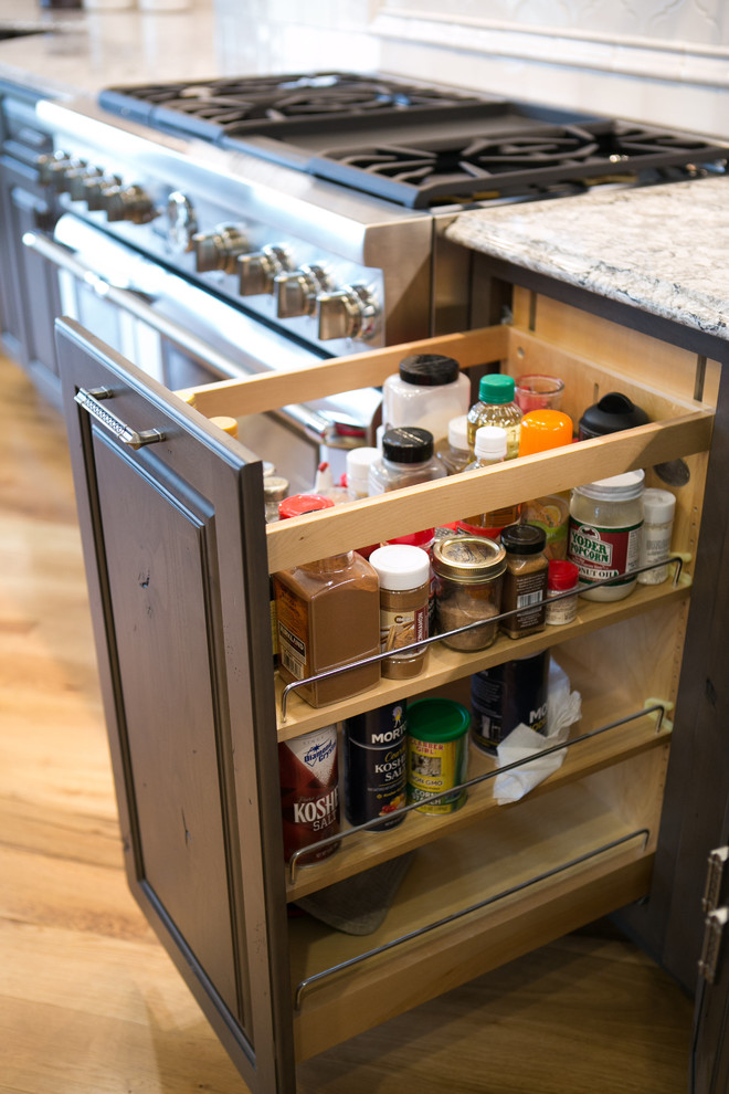 Kitchen - large transitional u-shaped medium tone wood floor and brown floor kitchen idea in Indianapolis with a farmhouse sink, raised-panel cabinets, dark wood cabinets, granite countertops, white backsplash, subway tile backsplash, paneled appliances, an island and multicolored countertops