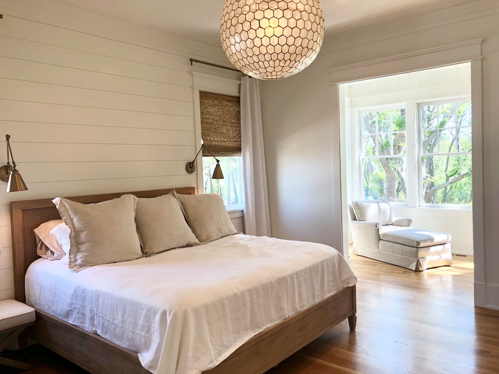 This is an example of a large country master bedroom in Charleston with white walls, medium hardwood floors, brown floor and no fireplace.