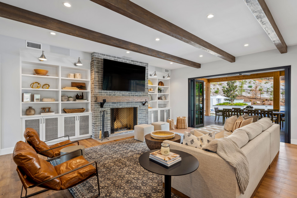 Huge country open concept light wood floor, beige floor and exposed beam living room photo in Los Angeles with white walls, a standard fireplace, a stone fireplace and a wall-mounted tv