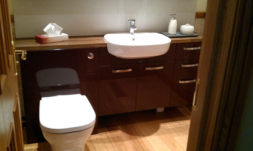 This is an example of a mid-sized contemporary powder room in Other with wood benchtops.