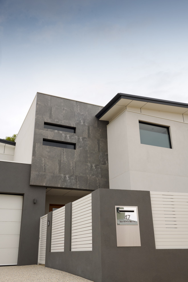 Large modern two-storey concrete grey house exterior in Perth with a butterfly roof, a metal roof and a black roof.