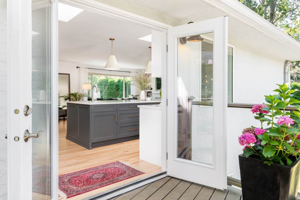 Large transitional l-shaped light wood floor and beige floor open concept kitchen photo in Vancouver with an undermount sink, recessed-panel cabinets, white cabinets, quartz countertops, white backsplash, ceramic backsplash, stainless steel appliances, an island and white countertops