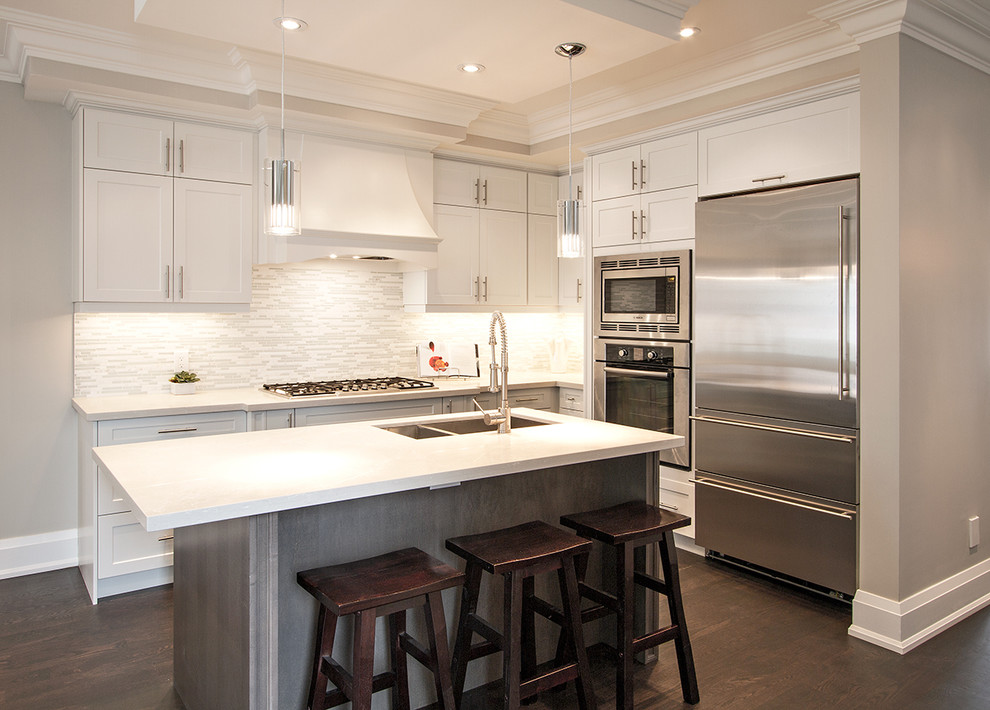 This is an example of a mid-sized contemporary u-shaped eat-in kitchen in Toronto with shaker cabinets, light wood cabinets, white splashback, dark hardwood floors, an undermount sink, mosaic tile splashback, stainless steel appliances, with island, brown floor and white benchtop.