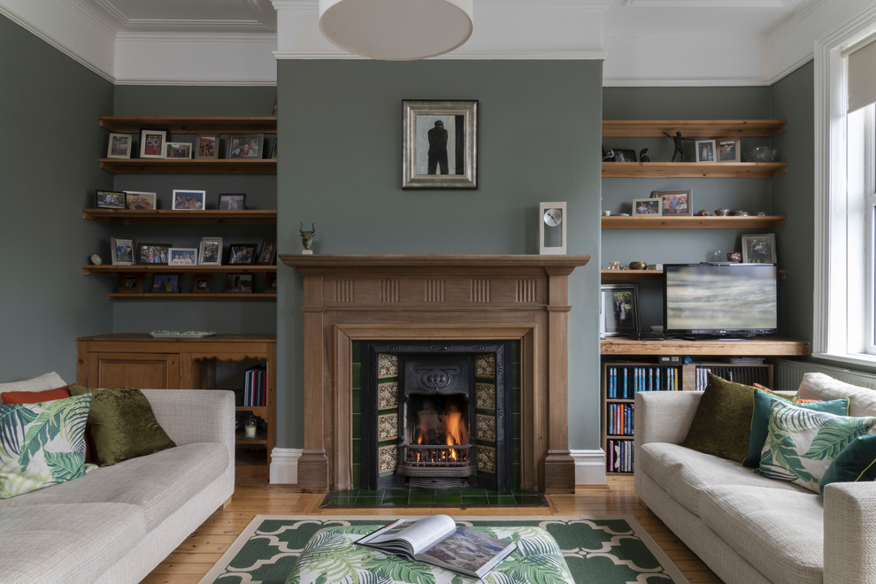 This is an example of a transitional living room in Other with green walls, medium hardwood floors, a standard fireplace, a tile fireplace surround and brown floor.
