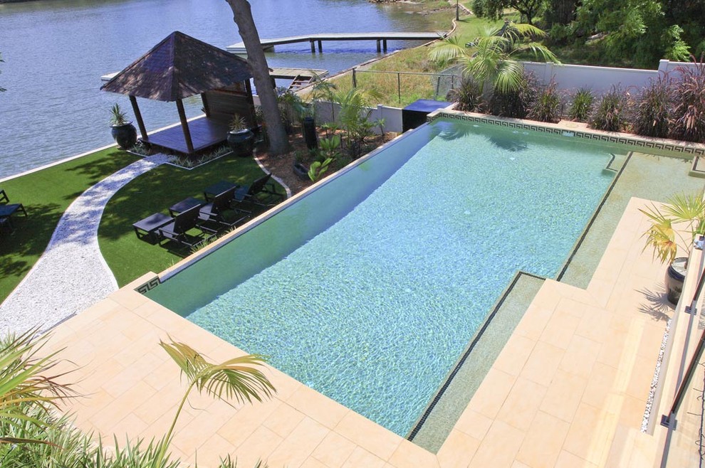 Inspiration for a mid-sized contemporary backyard rectangular infinity pool in Sydney with concrete pavers.