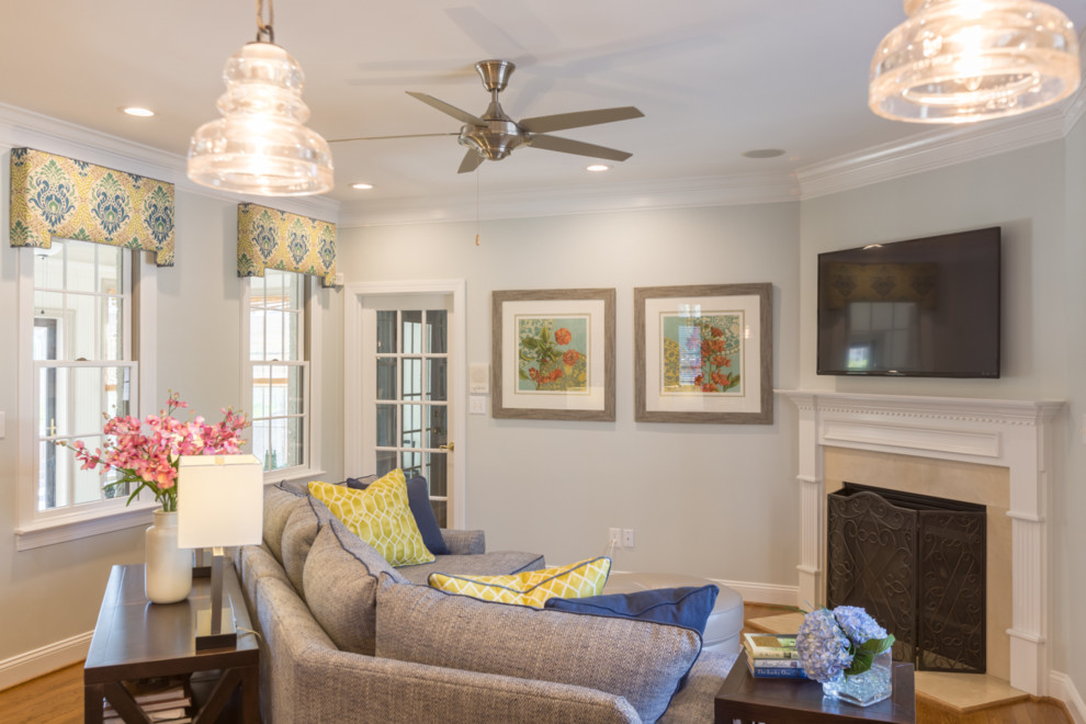 Mid-sized traditional open concept family room in Raleigh with grey walls, medium hardwood floors, a standard fireplace, a tile fireplace surround, a wall-mounted tv and brown floor.
