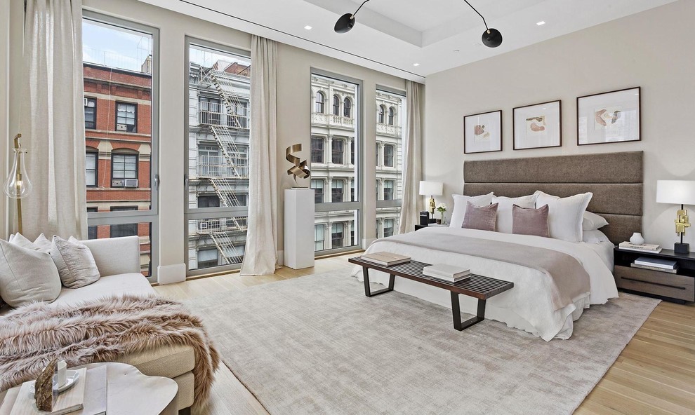 Photo of a contemporary bedroom in New York with beige walls, light hardwood floors and beige floor.
