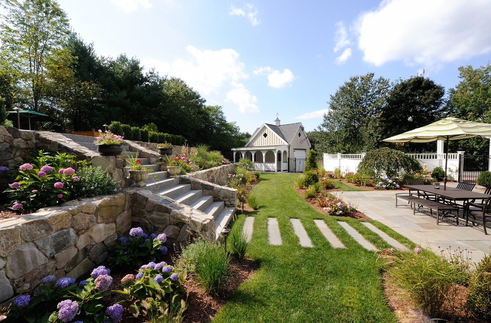 Inspiration for an expansive contemporary backyard garden in Boston with a retaining wall and natural stone pavers.