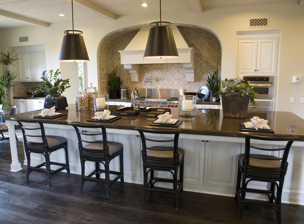 Kitchen - transitional l-shaped dark wood floor and gray floor kitchen idea with a farmhouse sink, recessed-panel cabinets, white cabinets, beige backsplash, porcelain backsplash, stainless steel appliances, an island and black countertops