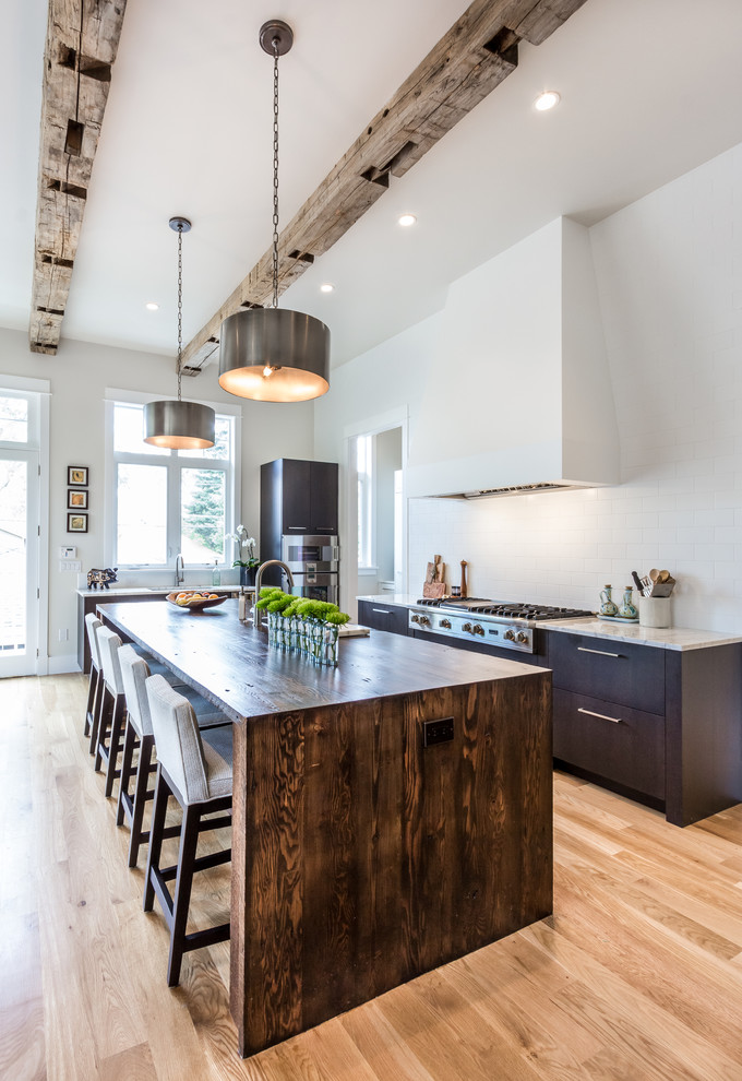 Large transitional u-shaped eat-in kitchen in Denver with grey cabinets, marble benchtops, white splashback, stainless steel appliances, light hardwood floors and with island.