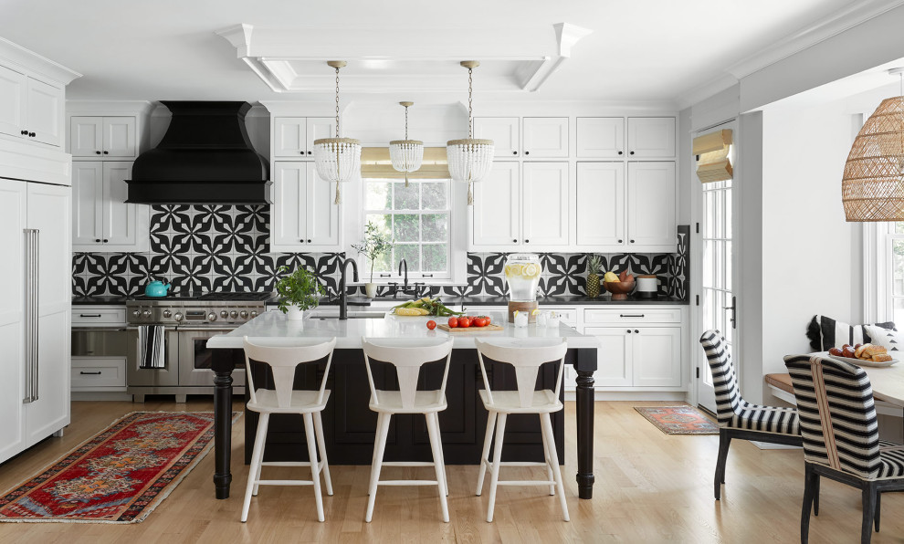 Inspiration for a transitional l-shaped light wood floor and beige floor eat-in kitchen remodel in Chicago with an undermount sink, beaded inset cabinets, white cabinets, multicolored backsplash, stainless steel appliances, an island and black countertops