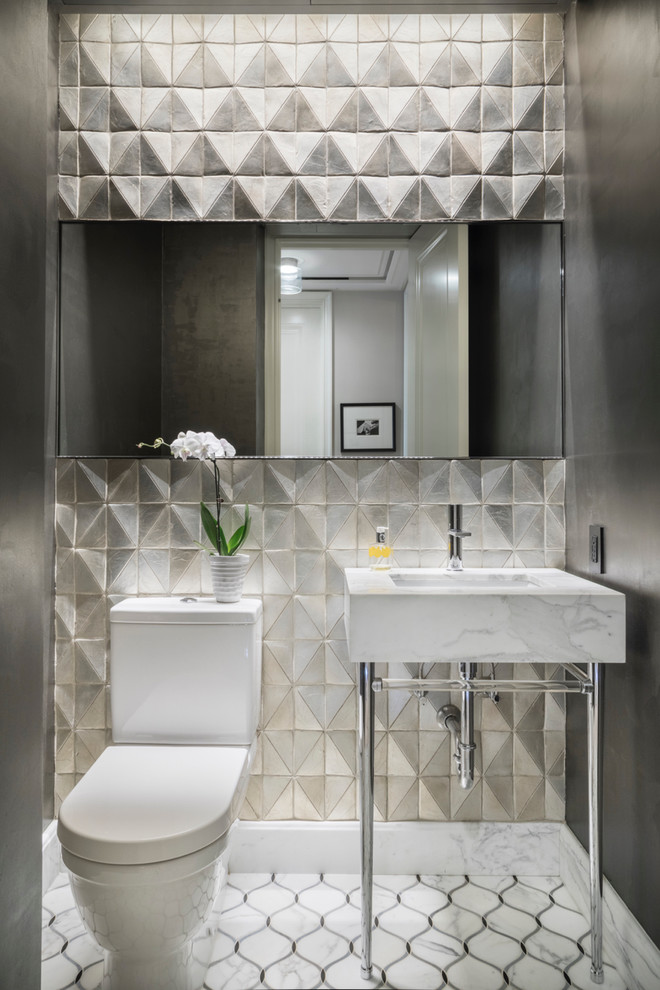 This is an example of a transitional powder room in New York with a two-piece toilet, gray tile, grey walls, marble floors, a console sink and multi-coloured floor.