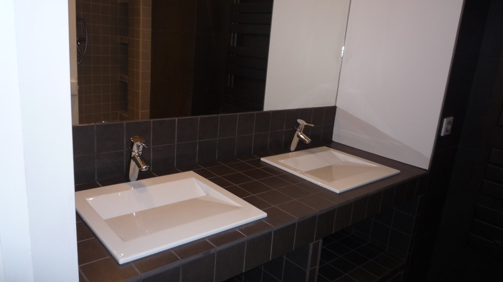 This is an example of a mid-sized contemporary master bathroom in Other with ceramic tile, open cabinets, black cabinets, an open shower, black tile, slate floors, an integrated sink and tile benchtops.